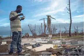  ?? RAMON ESPINOSA/AP ?? Jeffrey Roberts takes time for a meal Saturday amid the remnants of his relatives’ home after Hurricane Dorian ravaged the Bahamas.