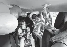  ??  ?? Caroline, left, and Keiley play and Georgianna, rear, looks out a window as Melanie Matcheson drives. The mother says she needs a minivan for her family of two adults and five kids.