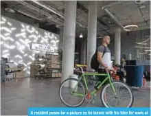  ??  ?? A resident poses for a picture as he leaves with his bike for work at the co-living building.