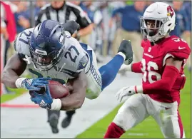  ?? RICK SCUTERI/AP PHOTO ?? Seattle Seahawks running back Mike Davis (27) dives in for a touchdown as Arizona Cardinals defensive back Budda Baker (36) defends during the first half of Sunday’s game at Glendale, Ariz. The Seahawks won 20-17.