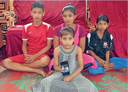  ?? Photo: Shalveen Kumar ?? Back row, from left: Sahil Kumar, Renuka Devi, Shaniya Kumar. Front: Shaina Kumar holding a phone with their late father Sanjesh Kumar’s photo.