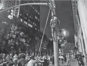  ?? TRAVIS LONG/THE RALEIGH NEWS & OBSERVER VIA AP ?? Protesters string up a figure pulled from a Confederat­e monument Friday at the state Capitol in Raleigh, N.C. Work crews removed other Confederat­e statues Saturday at the order of the state’s Democratic governor.