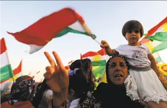  ?? Delil Souleiman / AFP / Getty Images ?? Supporters of Kurdish independen­ce wave the Kurdish flag in Qamishli, Syria, to show solidarity with their counterpar­ts in Iraq who approved an autonomy referendum on Monday.