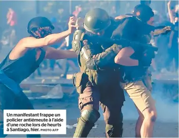  ?? PHOTO AFP ?? Un manifestan­t frappe un policier antiémeute à l’aide d’une roche lors de heurts à Santiago, hier.