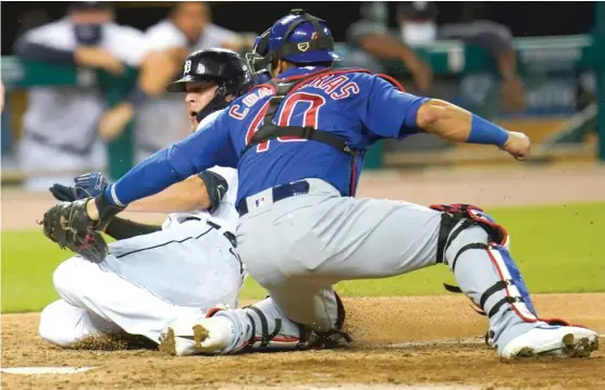  ?? PAUL SANCYA/AP ?? The Tigers’ JaCoby Jones slides around the tag of Cubs catcher Willson Contreras to score the first run in a five-run sixth inning Tuesday night in Detroit.