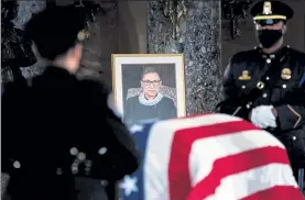  ?? ERIN SCHAFF / NYTNS ?? A portrait of Justice Ruth Bader Ginsburg overlooks her flag-draped casket as she lies in state at the Capitol in Washington on Friday.