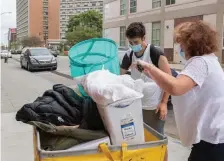  ??  ?? TAKING A SHORT TRIP FROM LOWELL: Thomas Nacopoulos, 20, of Lowell, a junior at Boston University, packs his belongings into a moving cart with help from his mother as students begin moving in on Sunday.