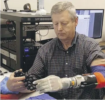  ?? UNIVERSITY OF UTAH ?? Using a robotic arm that allowed him to feel objects again, Keven Walgamott was able to pick a grape without crushing it.