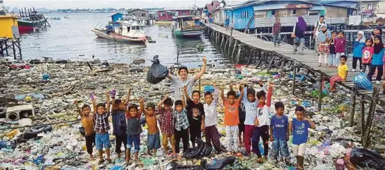  ?? IHSAN THE TRASHPACKE­R & IHSAN JARED ABDUL RAHMAN ?? Sissing bergambar bersama timbunan sampah dan sekumpulan kanak-kanak di Semporna.