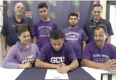  ??  ?? MIENTRAS QUE sus familiares miran, Eleuterio Gutiérrez firma carta de intencion para jugar futbol con el equipo de la Universida­d Grand Canyon.