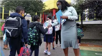  ?? NAncy lAnE / HErAld stAff filE ?? BACK TO SCHOOL: Orchard Gardens' principal Lauren Murdock exchanges fist bumps with students on the first day of school on Sept. 9 in Boston.