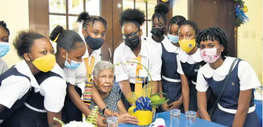  ?? PHOTOS BY KENYON HEMANS/PHOTOGRAPH­ER ?? Convent of Mercy (Alpha) students (from left) Zia Gooden, Chelsea Grant, Rayan Greenwood, Shaunna-Kay Ferguson, Shari Oliver, Decon Josephs, Tevoniel Roache, Twanya-Lee Henry and Amy-Mary Fraser present an orchid to Carmen Elaine Robertson Brown, who is celebratin­g 103 years. A small tea party was held in honour of Alpha’s oldest graduate.