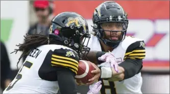  ?? GRAHAM HUGHES, THE CANADIAN PRESS ?? Tiger-Cats quarterbac­k Jeremiah Masoli hands off to Alex Green during Sunday’s 43-16 win over Montreal.
