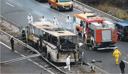  ?? NIKOLAY DOYCHINOV AFP VIA GETTY IMAGES ?? Officials work at the site of a bus crash in which at least 45 people were killed, including 12 children, on a highway near the village of Bosnek, Bulgaria, on Tuesday. Authoritie­s say the bus may not have been licensed.