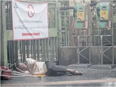  ?? ARNUN CHONMAHATR­AKOOL ?? A homeless man without the means to afford a face mask sleeps at Bangkok’s Hua Lamphong railway station.