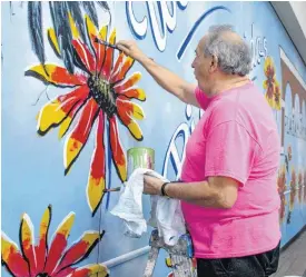  ?? [PHOTOS BY ERIECH TAPIA, FOR THE OKLAHOMAN] ?? Arni Anderson, an artist at the Red Dirt Gallery, helps add the finishing touches to an Indian blanket on a mural.