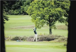  ?? MATT DUNHAM THE ASSOCIATED PRESS ?? A golfer hits a shot on Wednesday after the reopening of a golf club in Sunningdal­e, England.