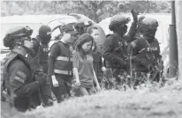  ?? Associated Press ?? Indonesian suspect Siti Aisyah, center, in the ongoing assassinat­ion investigat­ion, is escorted by police officers today as she arrives at Sepang court in Sepang, Malaysia.