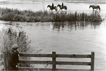  ??  ?? A boy looks across the flooding River Tame as riders pass by in the Sandwell Valley, West Bromwich, during the winter of 1958.