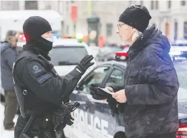  ?? Graham Hughes / the cana dian pres ?? A police officer issues a fine during a Dec. 20 demonstrat­ion in Montreal. Quebec’s new COVID restrictio­ns will be enforced with fines of between $1,000 and $6,000.