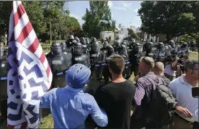  ?? STEVE HELBER — THE ASSOCIATED PRESS ?? White nationalis­t demonstrat­ors hold their ground against Virginia State Police as police fire tear gas rounds in Lee Park in Charlottes­ville, Va., Saturday, Aug. 12.