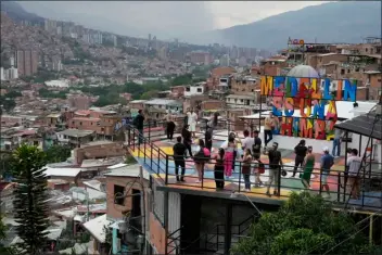  ?? FERNANDO VERGARA — THE ASSOCIATED PRESS ?? Tourists take photos in the Comuna 13neighbor­hood of Medellin, Colombia, Friday, Feb. 2, 2024. Once a battlegrou­nd for fighting among drug cartels, leftist guerrillas, military forces and government-linked paramilita­ry groups, the area is now a tourist attraction.