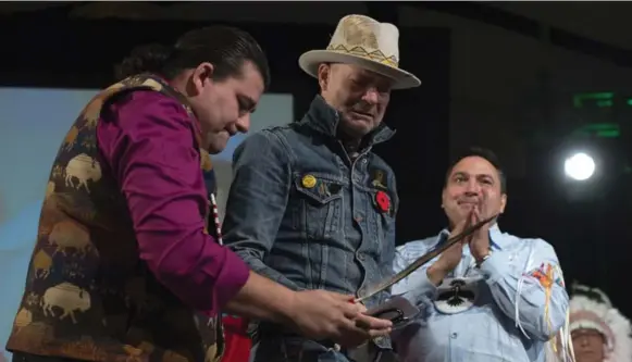  ?? ADRIAN WYLD/THE CANADIAN PRESS ?? Assembly of First Nations Chief Perry Bellegarde looks on as Lakota Sioux Donnie Speidel, left, presents Gord Downie with an eagle feather, an honoured gift from the Creator.
