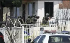  ?? DENIS POROY — THE ASSOCIATED PRESS ?? San Diego Police heavily armed police officers surround a house about a half-mile away, urging a man inside to surrender in San Diego Friday. One San Diego police officer was killed and another was wounded in a shootout following a late-night traffic...