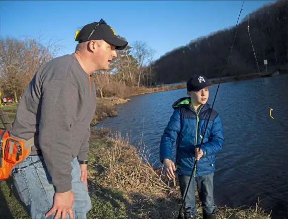  ?? Jessie Wardarski/Post-Gazette ?? Scott Karavlan, of McCandless, helps his son, Ronan, re-bait his hook after catching and releasing a trout at North Park Lake in March 2019.