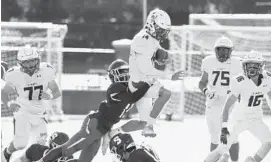  ?? PAUL W. GILLESPIE/BALTIMORE SUN MEDIA ?? St. Mary’s quarterbac­k Chris Golini leaps into the air on a run as Severn’s DaVaughn Joyner grasps at him in the second quarter.