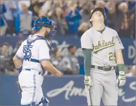  ?? The Canadian Press ?? Ryon Healy of the Oakland Athletics, right, reacts after striking out to end Monday’s game against the Toronto Blue Jays in Toronto. The Blue Jays won 4-2.