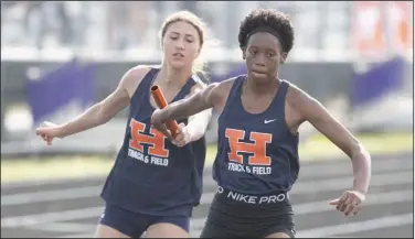  ?? (NWA Democrat-Gazette/J.T. Wampler) ?? Rogers Heritage High School’s Ella Fosse hands off the baton to Katherine Toney during the 4x200-meter relay at the 6A-West Conference track and field meet Wednesday in Fayettevil­le.