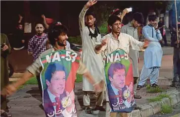  ??  ?? PENYOKONG PTI bersorak sambil memegang poster Imran Khan selepas parti itu diumumkan mendahului pilihan raya umum Pakistan semalam. - AFP