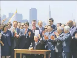  ?? Eric Risberg Associated Press ?? GOV. JERRY BROWN holds up a climate bill extending California’s capand- trade program after signing it at a ceremony in San Francisco in 2017.