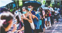  ?? ISAAC LAWRENCE/AFP via Gett y Images ?? A woman uses her phone while waiting to vote during
primary elections in Hong Kong on Sunday.