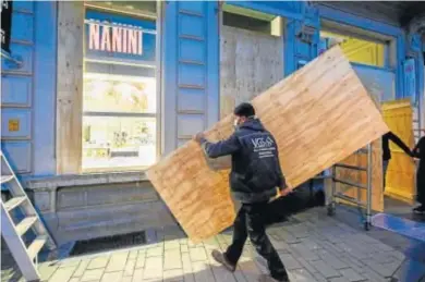  ?? JULIEN WARNAND / EFE ?? BLINDAJE. Los negocios se prepararon ayer en Turnhout (Bélgica), donde se colocaron paneles de madera en las tiendas para protegerla­s por temor a las protestas contra el toque de queda. Esta localidad está cercana a la frontera con Países Bajos, donde las manifestac­iones han sido continuas esta semanas.