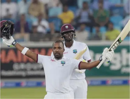  ?? — AFP ?? DUBAI: West Indies batsman Darren Bravo (front) raises his bat and helmet as he celebrates after scoring century (100 runs) as team captain Jason Holder looks on on the final day of the first day-night Test between Pakistan and the West Indies at the...