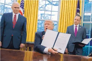  ?? EVAN VUCCI/ASSOCIATED PRESS ?? President Donald Trump shows off an executive order to withdraw the U.S. from the TransPacif­ic Partnershi­p trade pact Monday in the Oval Office. Behind him are Vice President Mike Pence, left, and Chief of Staff Reince Priebus.