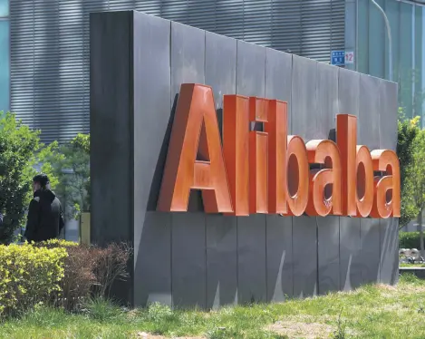  ??  ?? Two employees chat behind an Alibaba sign outside the company’s office in Beijing, China, April 13, 2021.