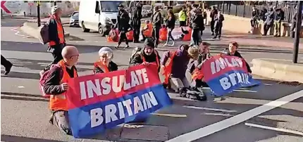  ?? ?? Insulate Britain campaigner­s block the A4400. Below, a banner is seized but was quickly replaced by the group