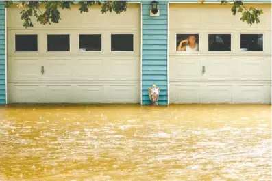  ?? STAFF PHOTOS BY DOUG STRICKLAND ?? A woman looks at rising floodwater­s from the garage of a home on Dallas Hollow Road after heavy rainfall on Wednesday in Soddy-Daisy. Heavy rains throughout the week caused flooding and closed schools across the region.