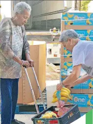  ??  ?? ABOVE: Olivia Walter, 75, waits as volunteer Mari Rupert, of Edmond, puts bananas in her cart during the Regional Food Bank of Oklahoma’s Fresh Food Mobile Market stop at the Danforth Senior Center on N Meridian Avenue.
