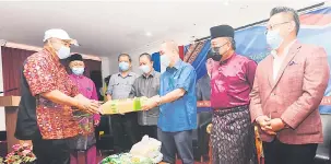  ??  ?? BANTUAN: Hajiji (tiga kanan) menyampaik­an bantuan Bakul Makanan B40 kepada seorang wakil penduduk bagi DUN Sulaman.