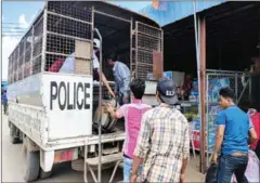  ?? MARYANN BYLANDER ?? Cambodian migrant workers unload bags at the Poipet border from a truck that deported workers from Thailand last week.