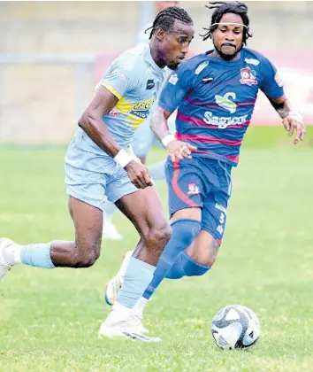  ?? GLADSTONE TAYLOR/MULTIMEDIA PHOTO EDITOR ?? Javane Bryan (left) of Waterhouse is chased by Dunbeholde­n’s Kevin Graham during their Jamaica Premier League match at the Drewsland Mini Stadium yesterday.