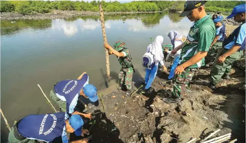  ?? RAMADA KUSUMA/JAWA POS RADAR BANYUWANGI ?? KOMPAK: Siswa dan relawan SAR bergabung dengan anggota TNI menanam ribuan mangrove di Pulau Santen kemarin. Tanaman mangrove berfungsi mencegah abrasi.