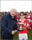  ??  ?? Coiste na nÓg chairman Pat Dunne presents Gleenaly’s Michael Óg O’Neill with the ‘A’ cup. O’Neill also collected the Wicklow People sponsored Man of the Match award.