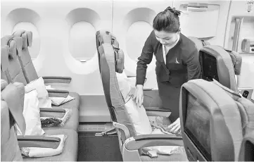  ??  ?? A flight attendant adjusts an economy-class seat onboard an Airbus A350-900 aircraft operated by Cathay Pacific Airways during a media event in Hong Kong, on May 30. — WP-Bloomberg photo