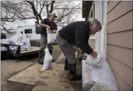  ?? PAUL KITAGAKI JR. — THE SACRAMENTO BEE VIA AP ?? Bill Bernstein and his son Will, lay sandbags around at the door of his home as they prepare for another storm Sunday in Maxwell The first outer rain bands from a powerful Pacific storm headed to Northern California on Sunday brought light rain and...