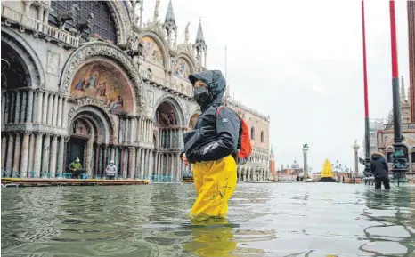  ?? FOTO: ANTEO MARINONI/DPA ?? Ein Bild aus Venedig, das es nicht mehr geben sollte: Eine Passantin bahnt sich ihren Weg durch den überflutet­en Markusplat­z. Starke Regenfälle und steigende Pegel hatten Teile der Stadt überflutet. Das Schutzsyst­em „Mose“wurde nicht aktiviert.